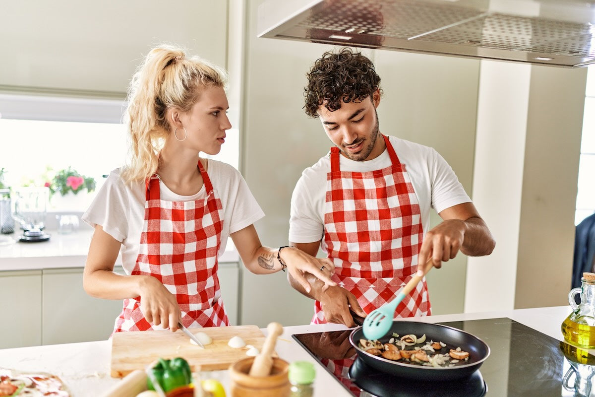 Pareja joven cocina con aceite de oliva virgen extra